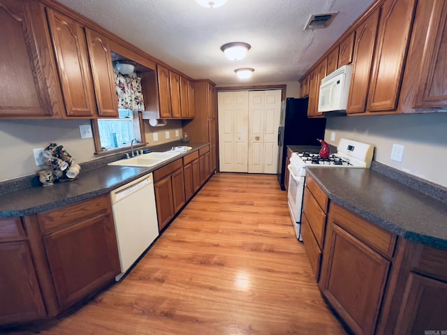 1702 Carolina Dr, Mena, AR 71953 - kitchen with white appliances, a sink, dark countertops, light wood-style floors, and brown cabinets