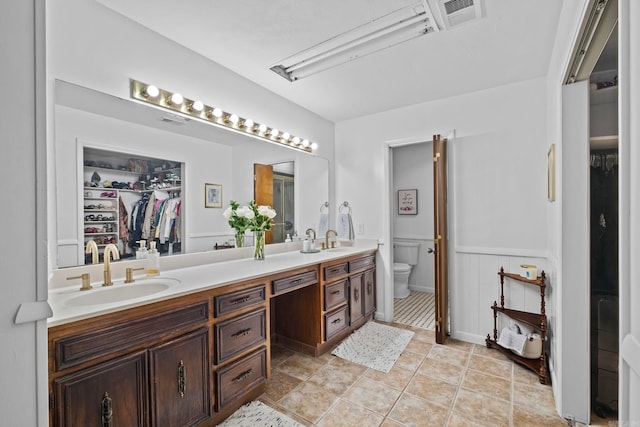 50 Heritage Park Cir, North Little Rock, AR 72116 - bathroom with toilet, double vanity, a walk in closet, and a wainscoted wall
