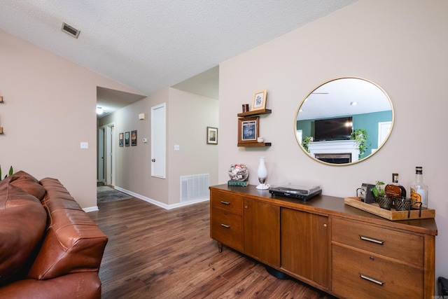 2418 Hickorynut Ct, Little Rock, AR 72211 - living room featuring dark wood-type flooring, lofted ceiling, baseboards, and a textured ceiling
