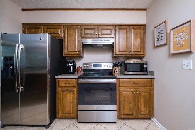 2418 Hickorynut Ct, Little Rock, AR 72211 - kitchen featuring stainless steel appliances, under cabinet range hood, light tile patterned flooring, brown cabinetry, and a textured ceiling