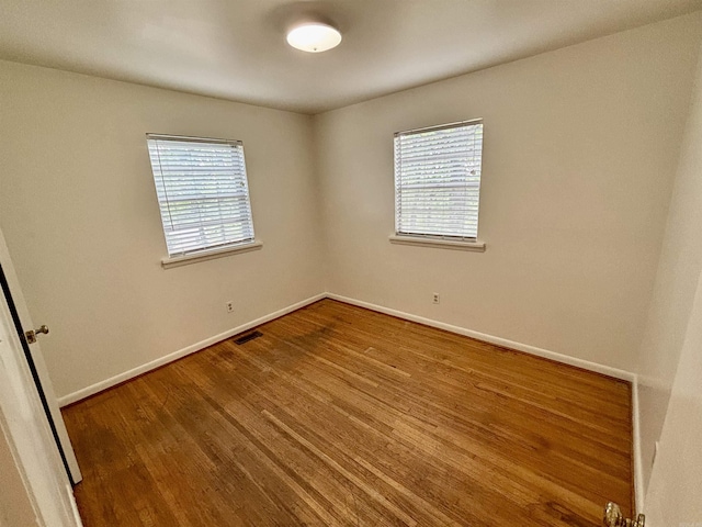 704 W 56th St, North Little Rock, AR 72118 - empty room featuring healthy amount of natural light, wood finished floors, and baseboards