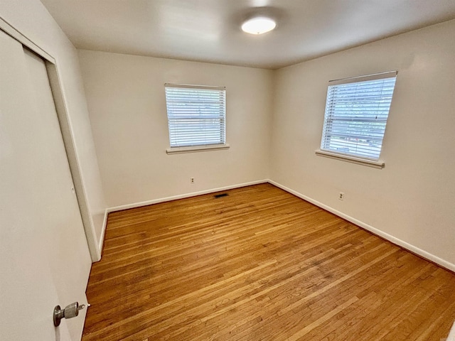704 W 56th St, North Little Rock, AR 72118 - unfurnished bedroom featuring multiple windows, baseboards, wood finished floors, and a closet