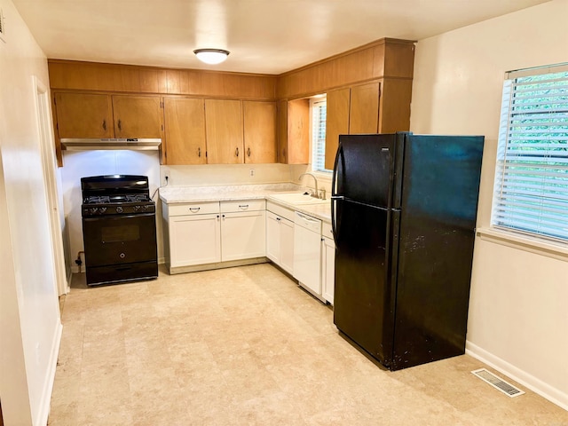 704 W 56th St, North Little Rock, AR 72118 - kitchen featuring black appliances, under cabinet range hood, light countertops, a sink, and light floors