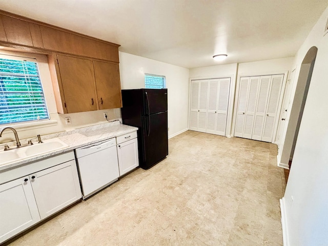 704 W 56th St, North Little Rock, AR 72118 - kitchen with white dishwasher, freestanding refrigerator, a sink, light countertops, and arched walkways