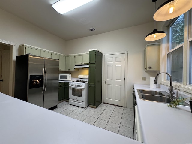 kitchen with green cabinetry, white appliances, a sink, under cabinet range hood, and light tile patterned flooring