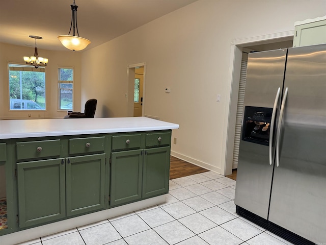kitchen with green cabinetry, stainless steel fridge with ice dispenser, a chandelier, light tile patterned floors, and pendant lighting