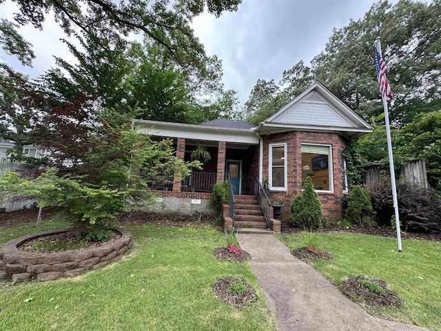 view of front of home with a front lawn, covered porch, and brick siding