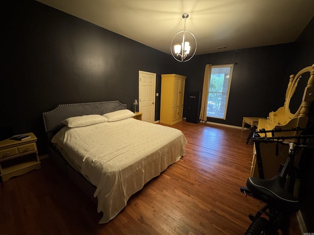 bedroom with wood finished floors, a chandelier, and baseboards