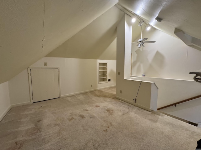 additional living space with vaulted ceiling, carpet floors, baseboards, and built in shelves