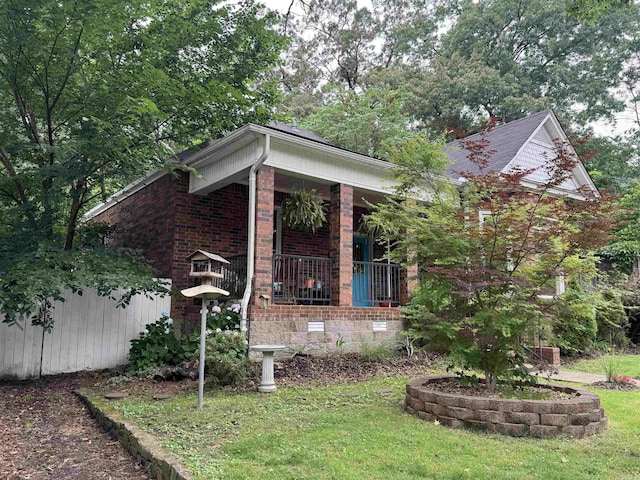 view of front facade featuring a porch, brick siding, a front yard, and crawl space