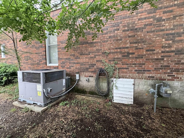 exterior view of central AC, crawl space, brick siding, and gas meter