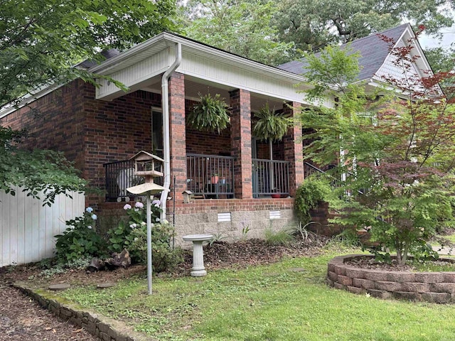 view of side of property featuring covered porch, crawl space, and brick siding
