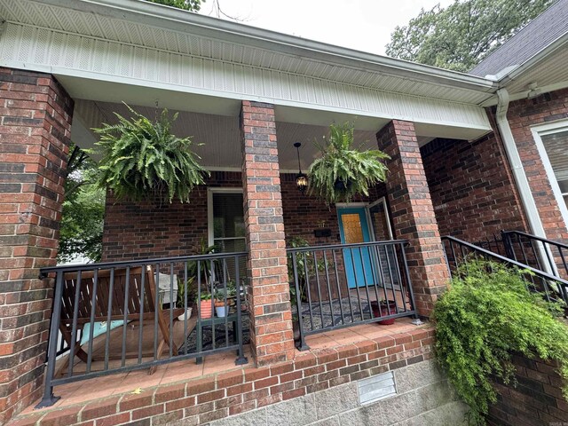 view of exterior entry featuring a porch and brick siding