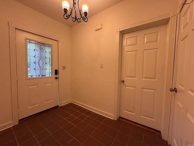 entrance foyer featuring dark tile patterned floors, a chandelier, and baseboards