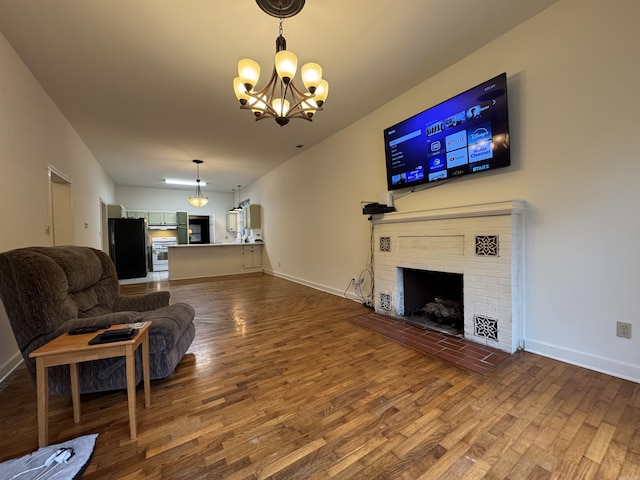 living area featuring wood finished floors, a chandelier, a fireplace, and baseboards