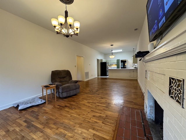 unfurnished room featuring a chandelier, dark wood finished floors, a brick fireplace, and baseboards