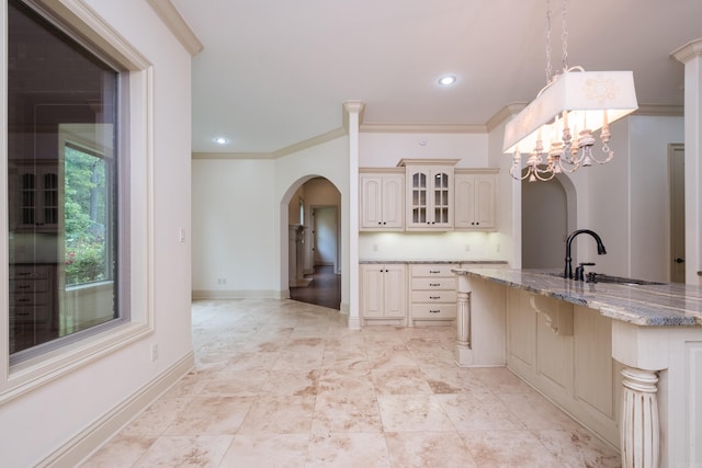 28 Talmont Pl, Little Rock, AR 72223 - kitchen with cream cabinets, arched walkways, a sink, glass insert cabinets, and light stone counters