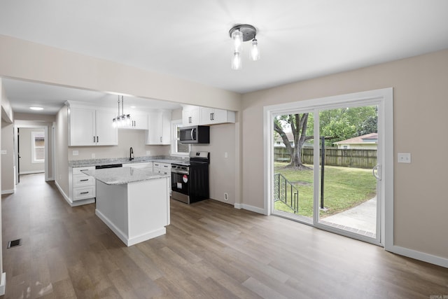 kitchen featuring stainless steel appliances, a sink, baseboards, wood finished floors, and white cabinets