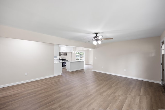 unfurnished living room with ceiling fan, wood finished floors, and baseboards