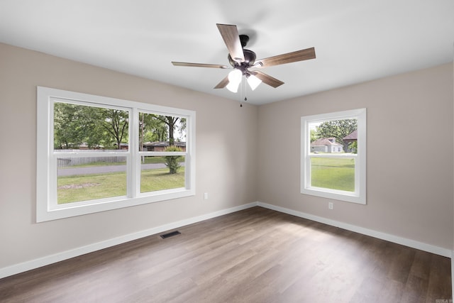 empty room with wood finished floors, baseboards, and a ceiling fan