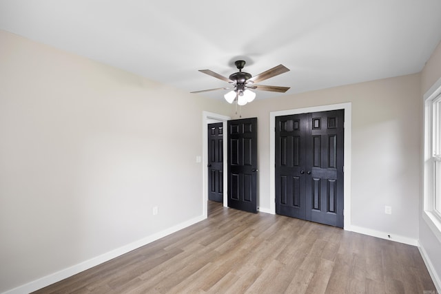 unfurnished bedroom featuring wood finished floors, baseboards, a closet, and a ceiling fan