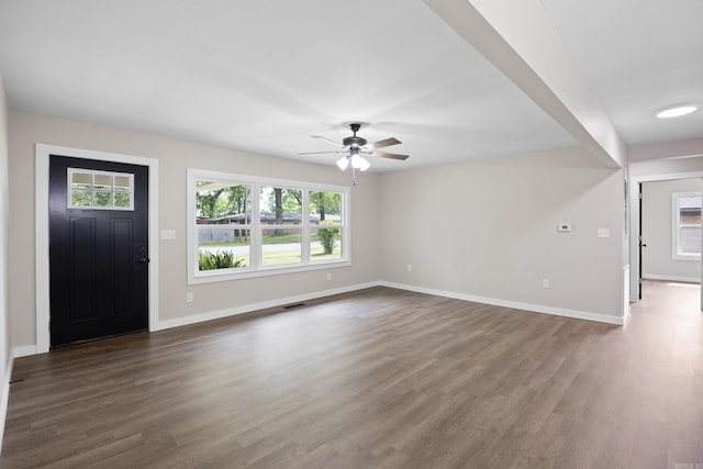 unfurnished living room with ceiling fan, baseboards, and dark wood-type flooring