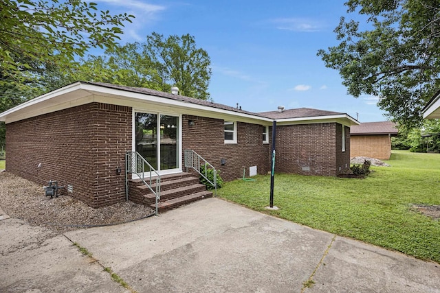 rear view of property featuring brick siding, entry steps, a lawn, and crawl space