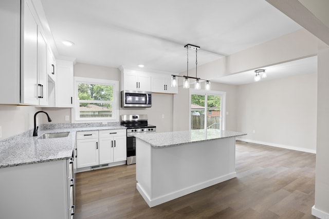 kitchen featuring stainless steel appliances, a sink, white cabinetry, wood finished floors, and recessed lighting