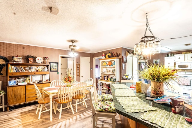 4531 Lee Road 225, Marianna, AR 72360 - dining space featuring light wood-style flooring, crown molding, a textured ceiling, a chandelier, and a ceiling fan