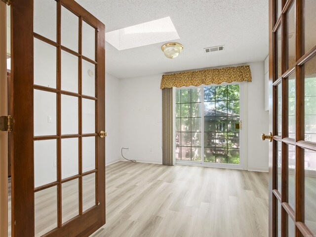 6 Sierra Ln, Hot Springs Village, AR 71909 - empty room featuring a skylight, wood finished floors, a textured ceiling, and french doors