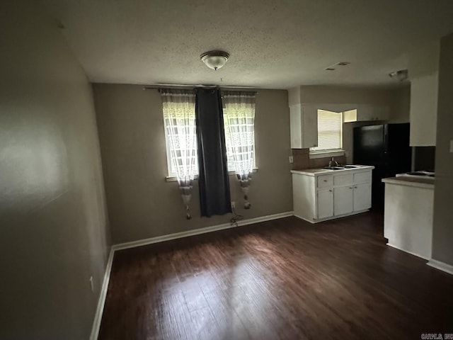 3509 Arapaho Trl, Little Rock, AR 72209 - unfurnished dining area with dark wood-type flooring, baseboards, a sink, and a textured ceiling