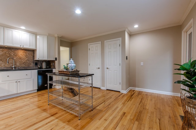 6220 Hopi Dr, North Little Rock, AR 72116 - kitchen with black dishwasher, a sink, light wood finished floors, tasteful backsplash, and white cabinets