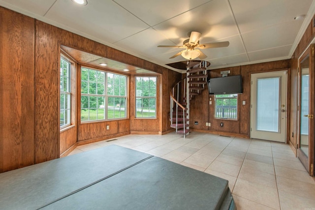 6220 Hopi Dr, North Little Rock, AR 72116 - unfurnished living room with wooden walls, healthy amount of natural light, stairs, a ceiling fan, and tile patterned flooring