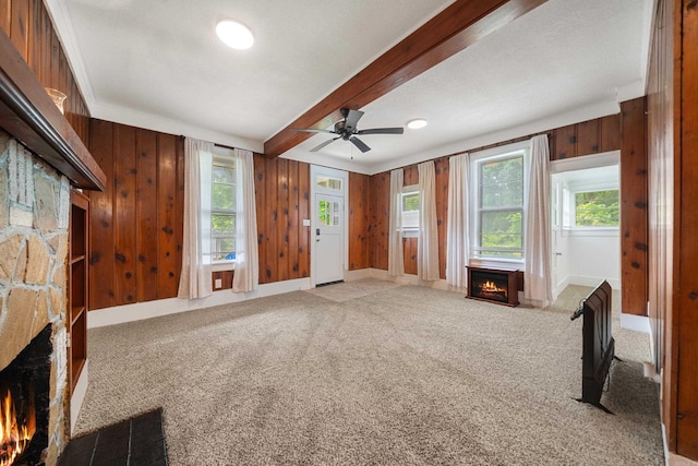 169 Crest St, Hot Springs, AR 71901 - unfurnished living room featuring a warm lit fireplace, wooden walls, carpet flooring, a ceiling fan, and beam ceiling