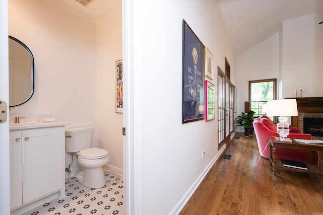 3501 Oakwood Rd Unit 9, Little Rock, AR 72202 - bathroom featuring toilet, baseboards, a brick fireplace, vanity, and wood finished floors
