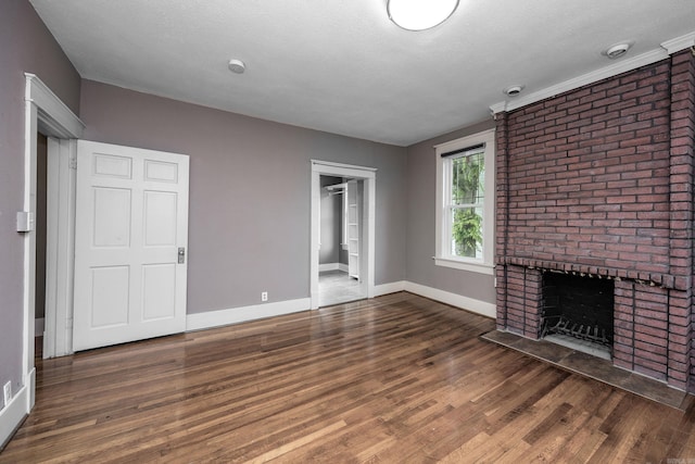 2118 S Battery, Little Rock, AR 72202 - unfurnished living room with wood finished floors, a brick fireplace, baseboards, and a textured ceiling
