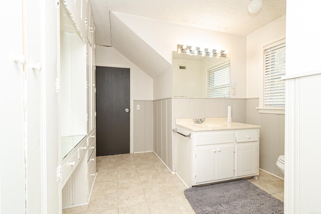 1002 N Bradley Ave, El Dorado, AR 71730 - bathroom with tile patterned flooring, toilet, a textured ceiling, a wainscoted wall, and vanity