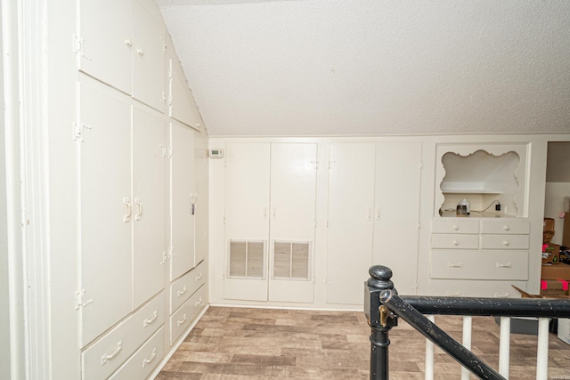 1002 N Bradley Ave, El Dorado, AR 71730 - corridor featuring lofted ceiling, light wood-style floors, and a textured ceiling
