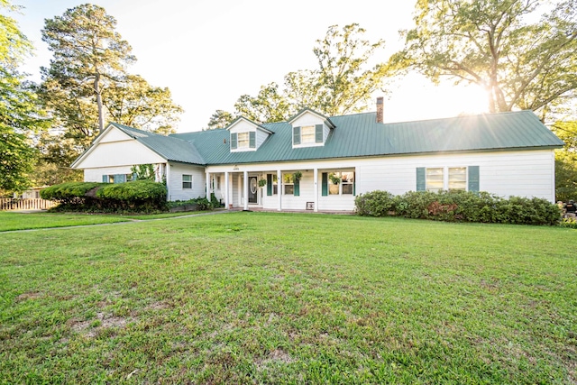 1002 N Bradley Ave, El Dorado, AR 71730 - cape cod-style house featuring a chimney, a porch, a front lawn, and metal roof