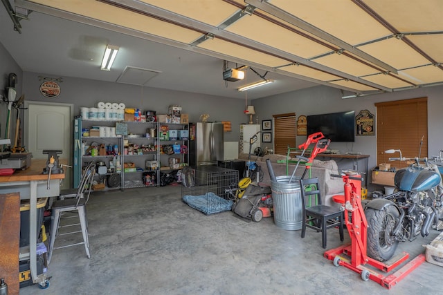 766 Mango Loop, Austin, AR 72007 - garage featuring freestanding refrigerator, a garage door opener, and a workshop area