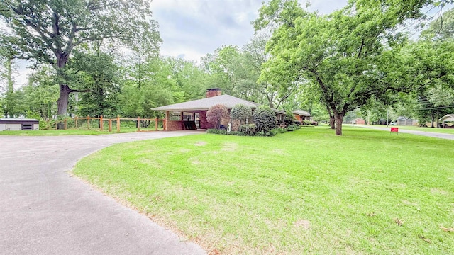 38 Wolfe, Mcgehee, AR 71654 - view of front of home with asphalt driveway, a chimney, view of scattered trees, and brick siding