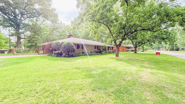 38 Wolfe, Mcgehee, AR 71654 - view of front facade with a chimney, driveway, a front lawn, and an attached carport