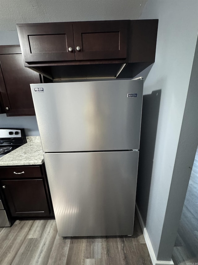 2314 Woodland Bluff Dr, Heber Springs, AR 72543 - kitchen view of appliances with stainless steel finishes, dark brown cabinets, light wood-style flooring, light countertops, and baseboards
