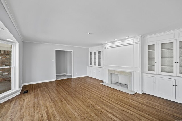 7011 W Markham St, Little Rock, AR 72205 - unfurnished living room with baseboards, crown molding, wood finished floors, recessed lighting, and built in shelves