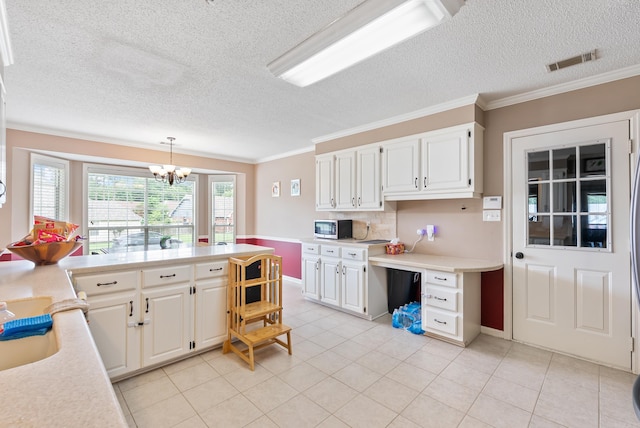 1 Forest Brook Ct, Little Rock, AR 72211 - kitchen featuring stainless steel microwave, light countertops, a chandelier, white cabinets, and a textured ceiling