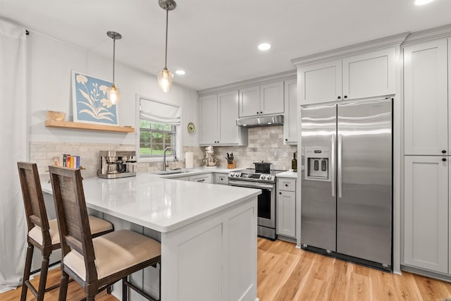 8010 Iowa Dr, Little Rock, AR 72227 - kitchen featuring stainless steel appliances, a sink, a peninsula, under cabinet range hood, and a breakfast bar