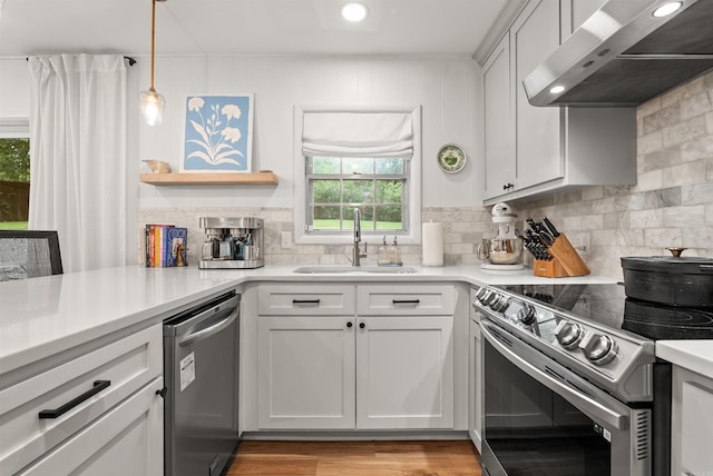 8010 Iowa Dr, Little Rock, AR 72227 - kitchen featuring stainless steel appliances, wall chimney range hood, a sink, decorative backsplash, and light countertops