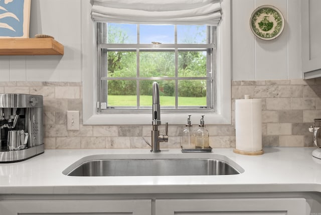 8010 Iowa Dr, Little Rock, AR 72227 - kitchen featuring a sink, backsplash, light countertops, and white cabinetry