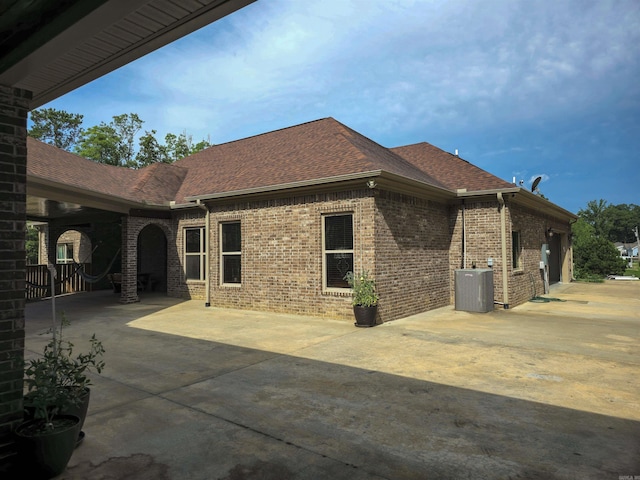 23 Whispering Dr, Alexander, AR 72002 - rear view of property featuring brick siding, a shingled roof, central AC unit, and concrete driveway
