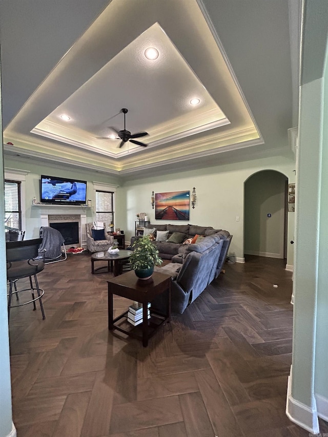 23 Whispering Dr, Alexander, AR 72002 - living area featuring a raised ceiling, arched walkways, crown molding, a ceiling fan, and a fireplace